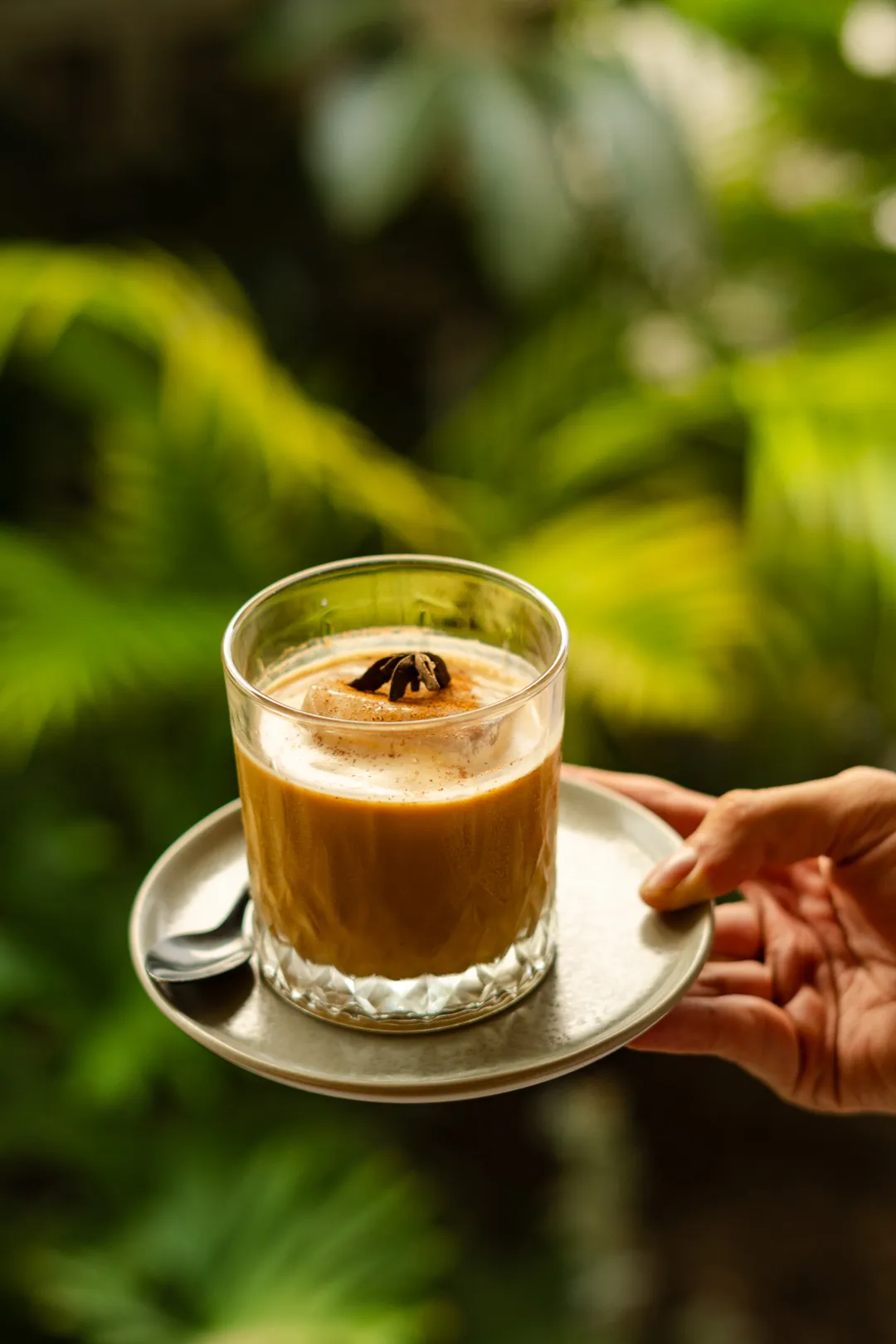 Spy Honey Latte servido sobre plato cerámico con plantas tropicales