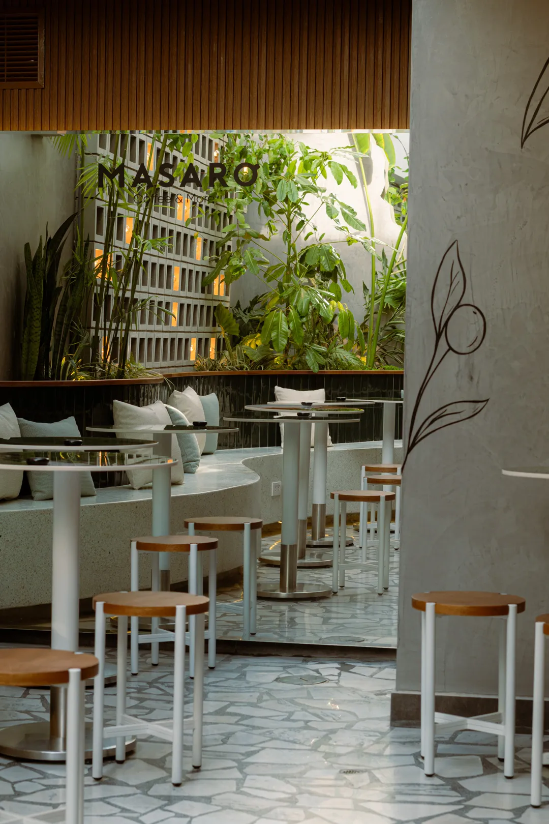 Interior de Masaro Coffee & More con plantas y la marca en pared