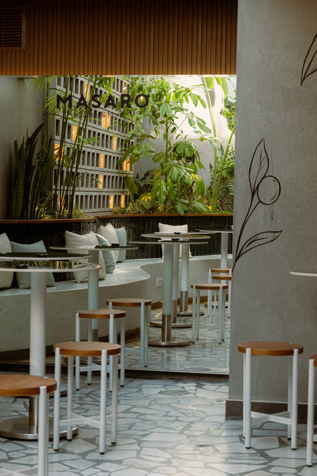 Interior de Masaro Coffee & More con plantas y la marca en pared